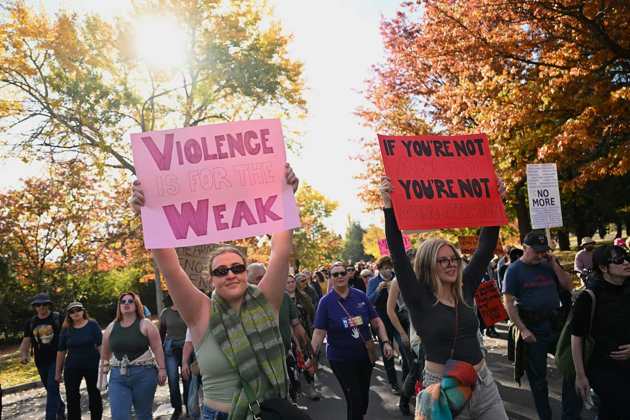 Women holding signs during a protest. One of the signs reads 