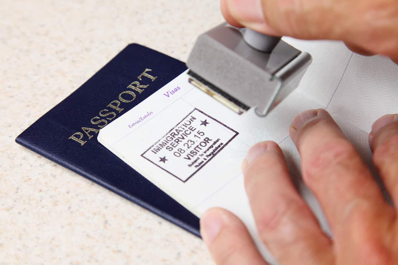 A hand holing a stamp about to place a stamp in a passport. 