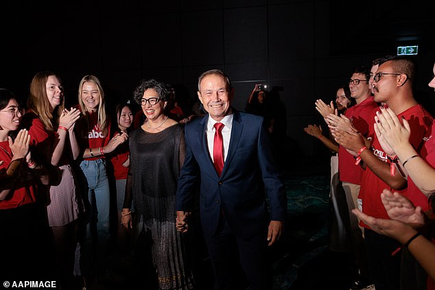 Premier Roger Cook (pictured, with his wife Carly Lane) has declared he's ready to get back to work after Western Australian Labor secured a third term with another massive victory
