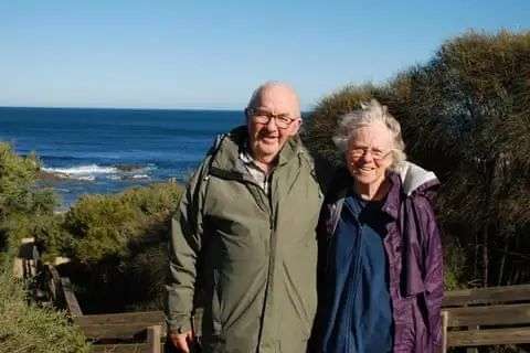 Don and Gail Patterson, an elderly couple posing against an ocean view backdrop