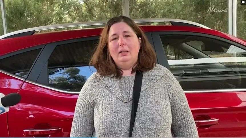 A woman standing in front of her car.