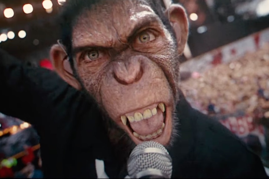 A CGI chimpanzee wearing ear monitors screams into a microphone and the camera