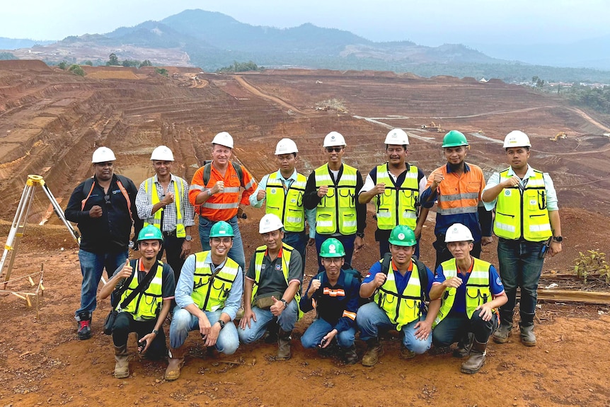 Group of workers in front of large mine open pit mine site.