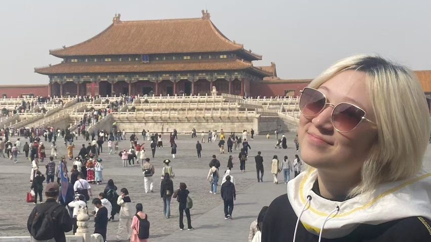 A woman poses for a photo in front of a temple.
