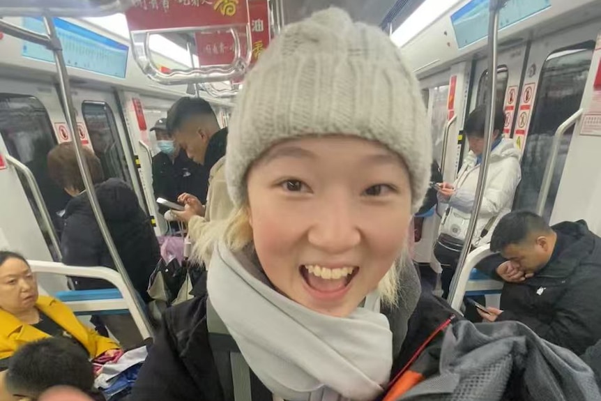 A woman wearing a beanie smiles at the camera.