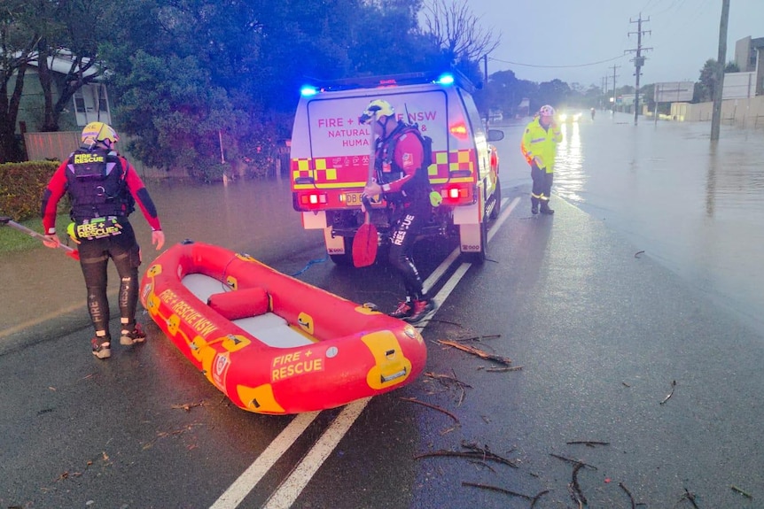 A flooded street with emergency service personnel nearby. 