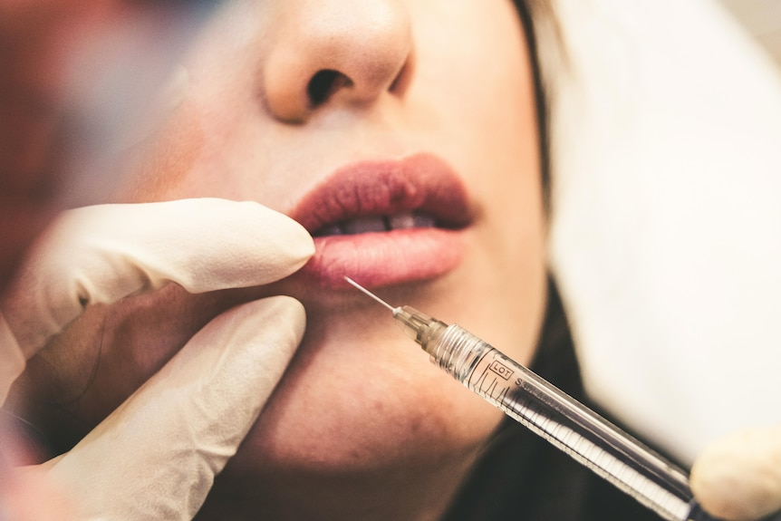 A woman having a cosmetic injectible in her lip.
