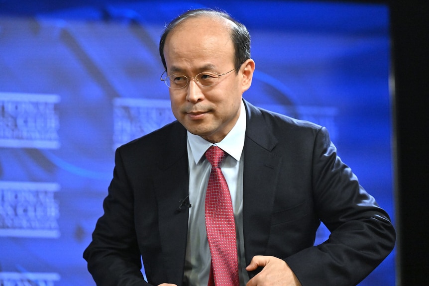 China's Ambassador to Australia Xiao Qian in a suit and glasses. 
