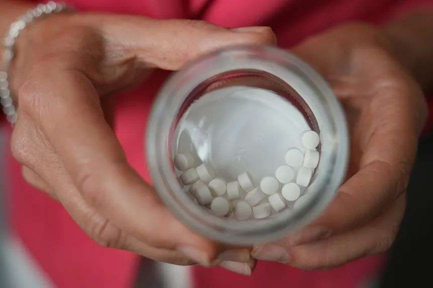 Hands holding a jar of pills.