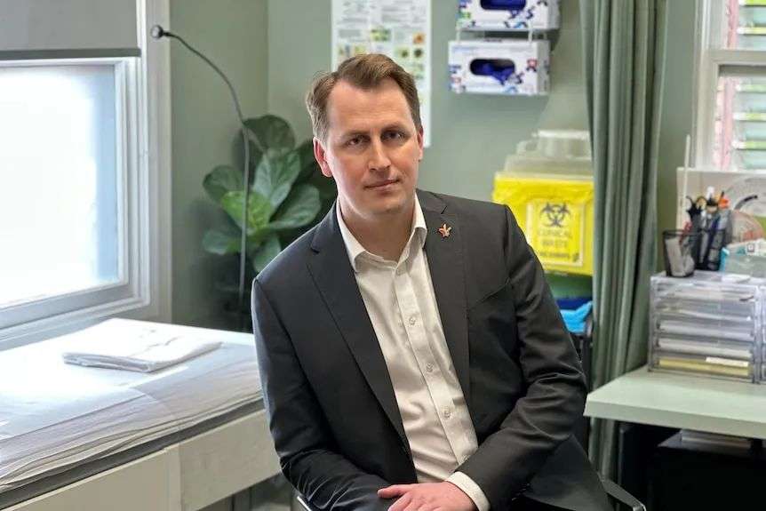 Man in a suit sitting in a patient room.