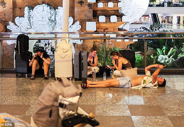 周一，伍拉·赖国际机场至少有24个航班被取消。图为滞留的旅客在等待航班延误。