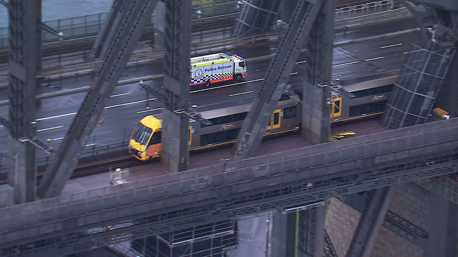 Train crossing Sydney Harbour Bridge, police vehicle passing in the background.