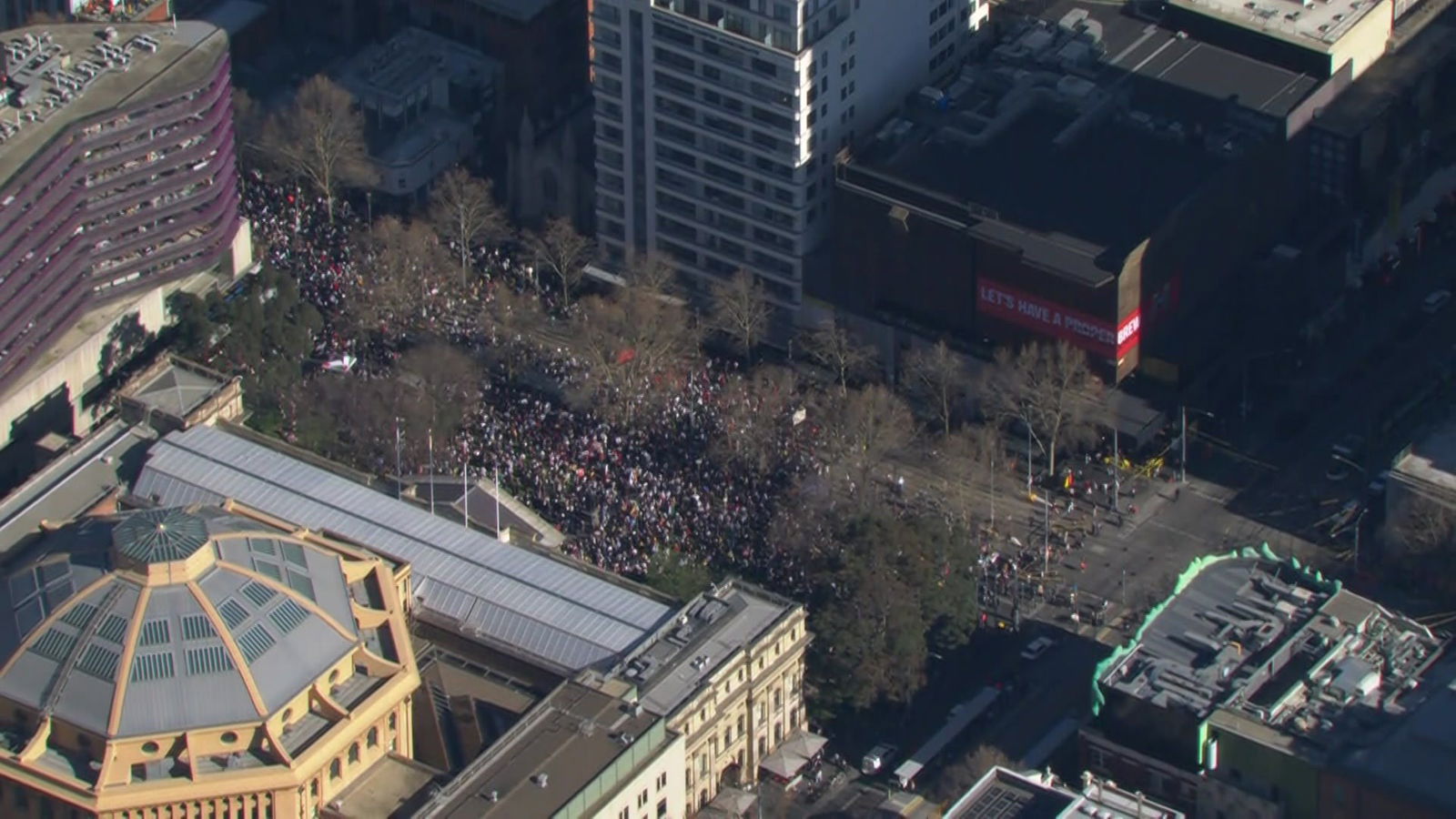 许多人站在城市街道上一座圆顶建筑旁边。