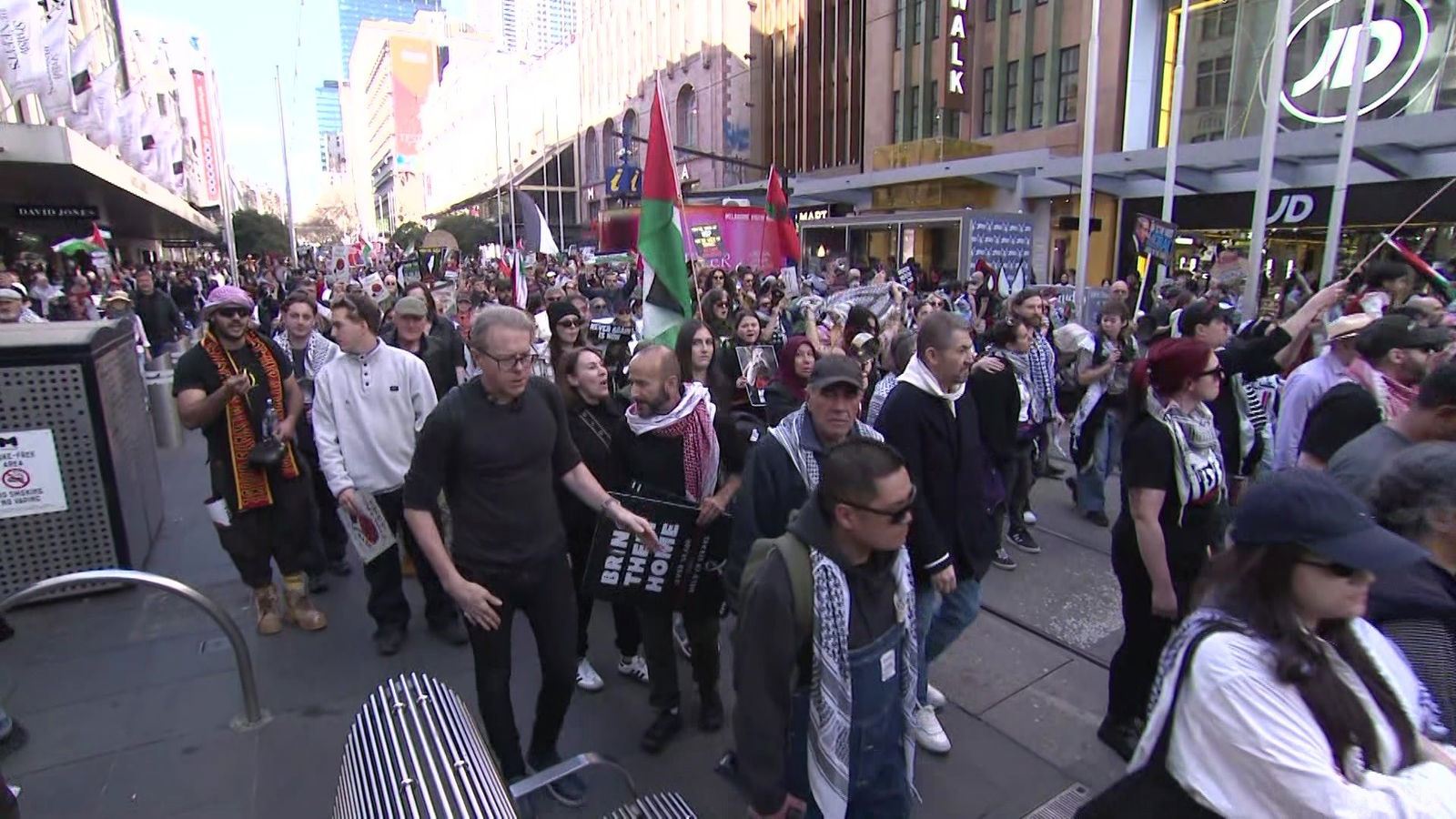 一大群人举着旗帜和标语沿着伯克街购物中心的中心游行。