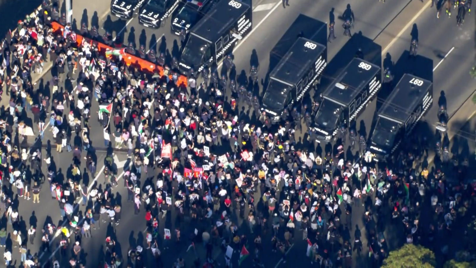 空中拍摄的大量人群站在路上,面对着一排防暴警察和黑色警车。