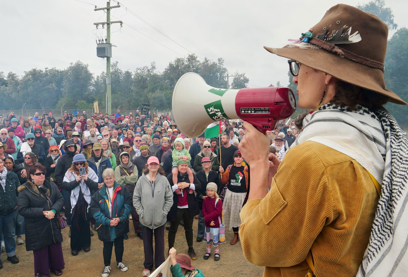 一位戴着棕色阿库拉式帽子的女士用扩音器向人群讲话