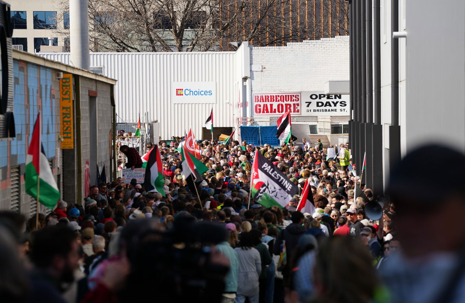 一群抗议者穿过城市小巷，其中一些人举着巴勒斯坦国旗。