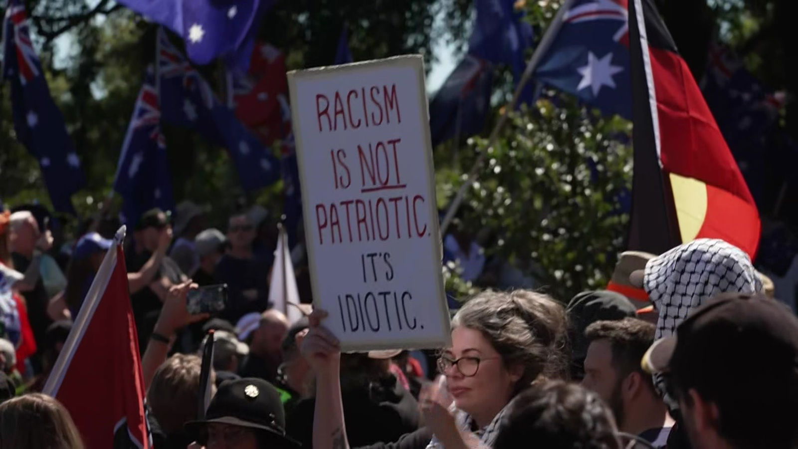 一个人举着一块牌子,上面写着“种族主义不是爱国”