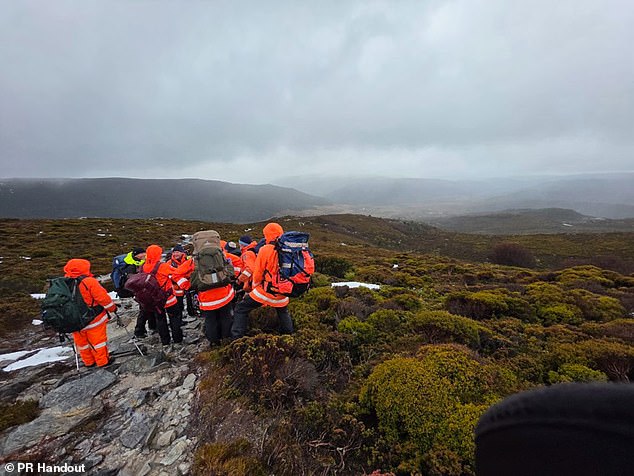 A woman is dead and others have been rescued from remote wilderness after a group of Chinese tourists set out for a hike unprepared for extreme weather (rescuers are pictured)