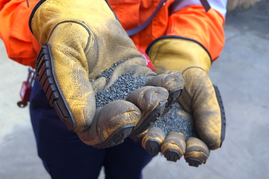 A person holds a handfull of ground nickel