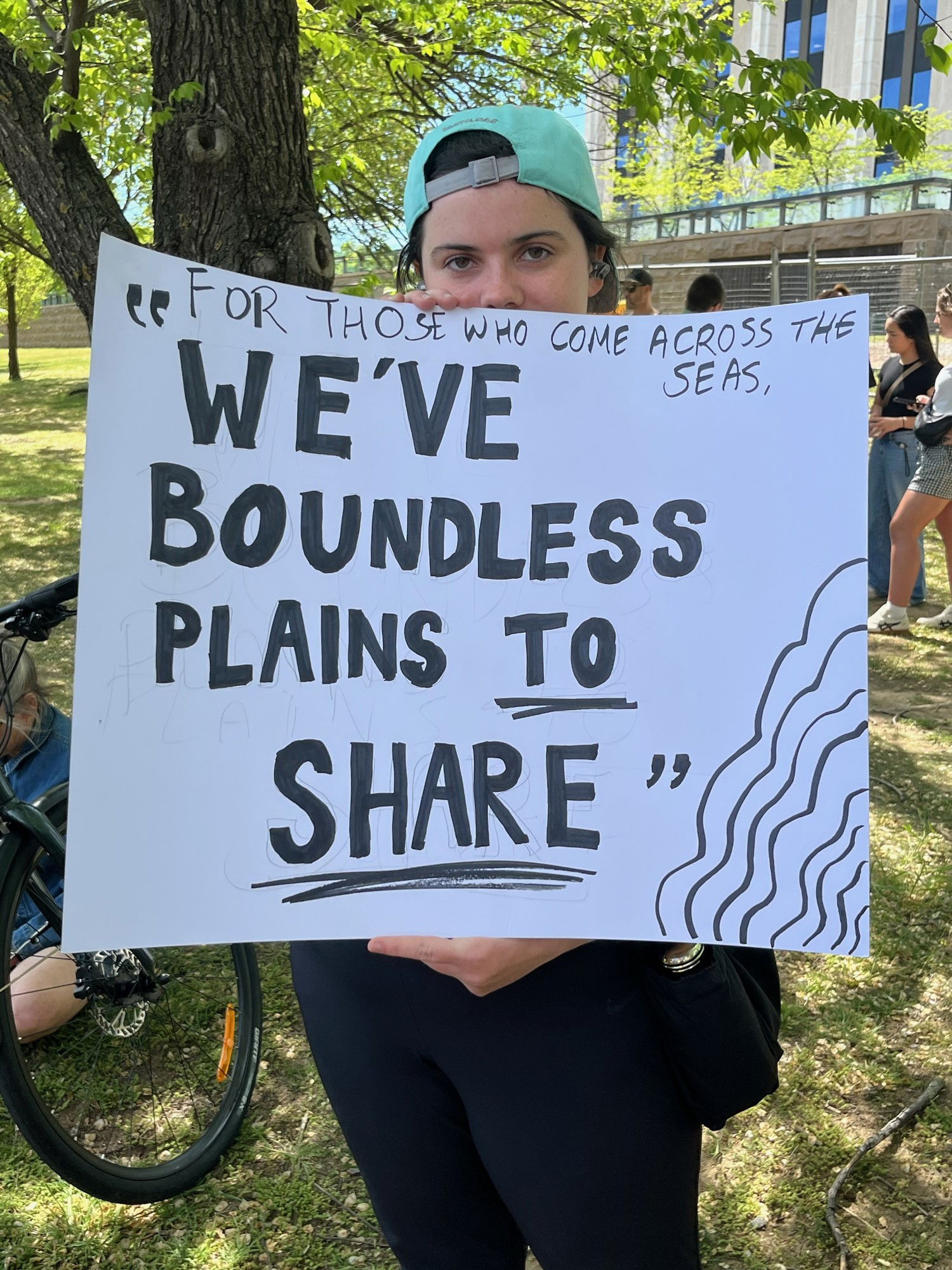 一个人举着一块牌子，上面写着“我们有无边无际的平原可以分享”