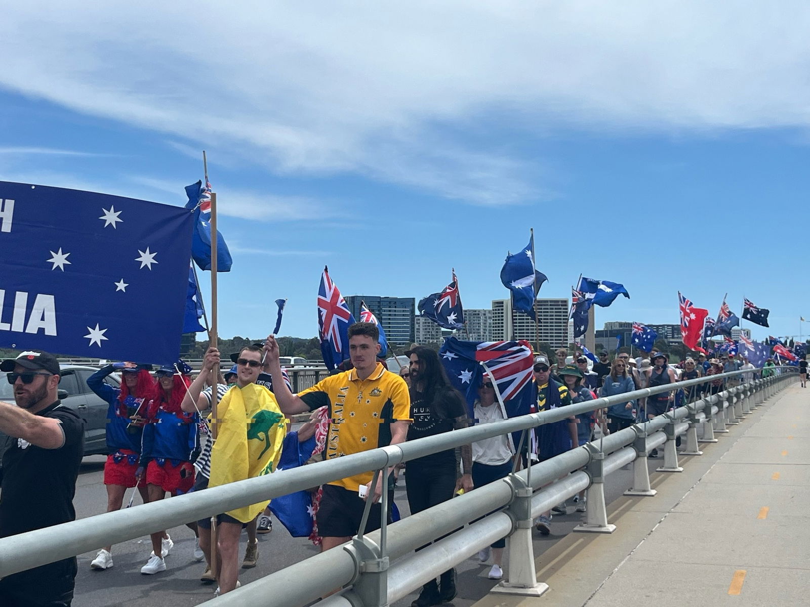 一群人举着澳大利亚国旗走过一座桥。