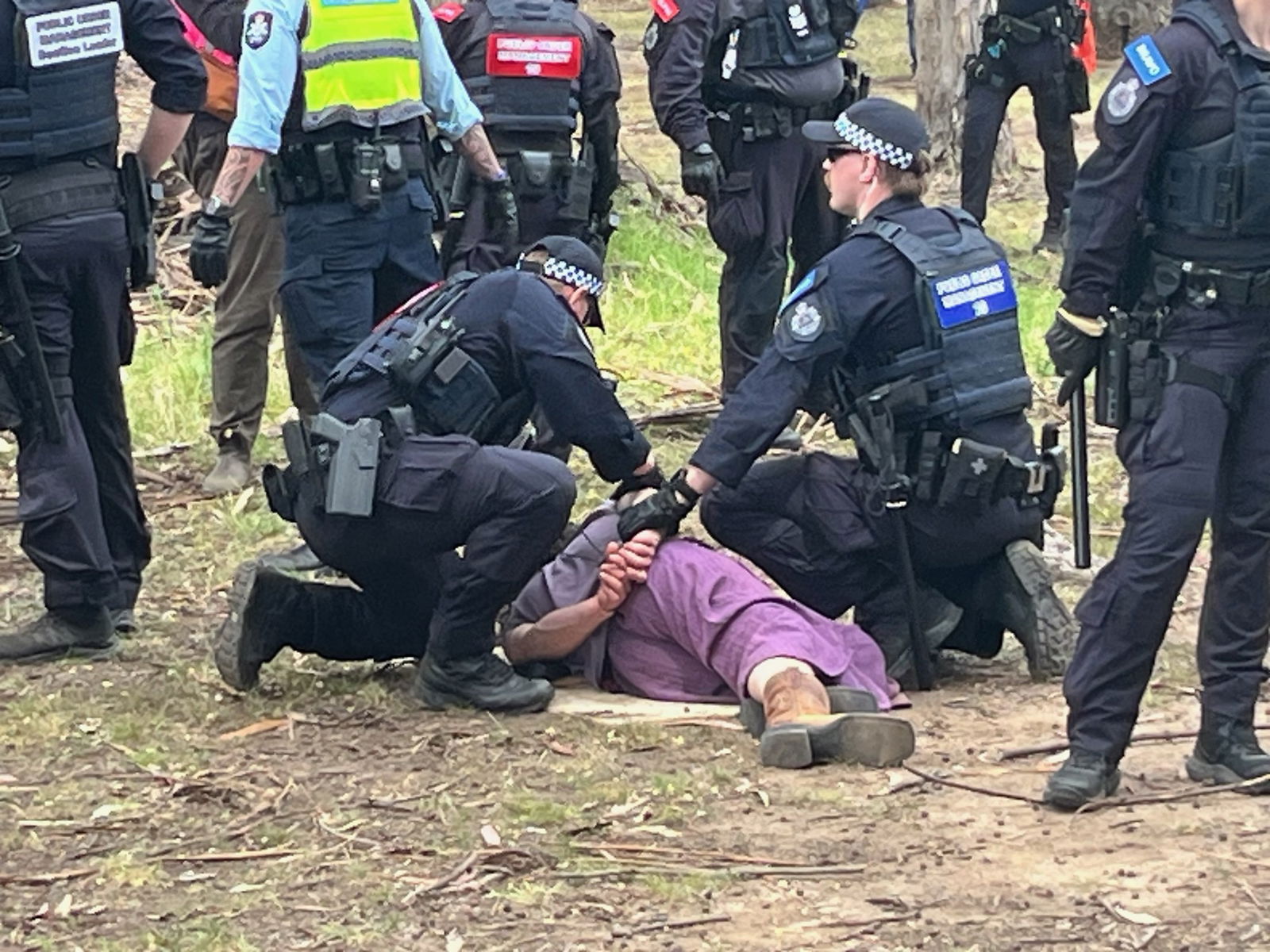 一名男子倒在地上，旁边有警察。