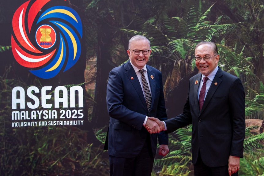 Anthony Albanese shaking hands with Anwar Ibrahim on a red carpet with the ASEAN logo behind them.
