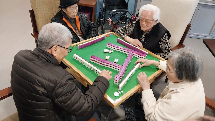 Four elderly people are playing mahjong.
