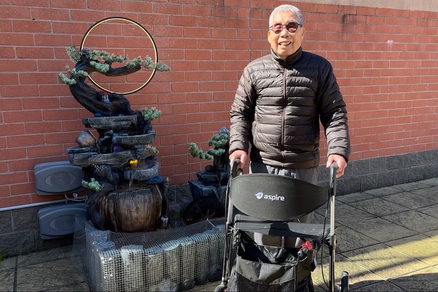 An elderly man standing with a walking frame
