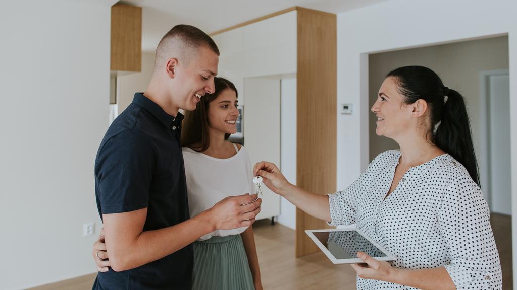 Estate agent handing keys to young couple in new house