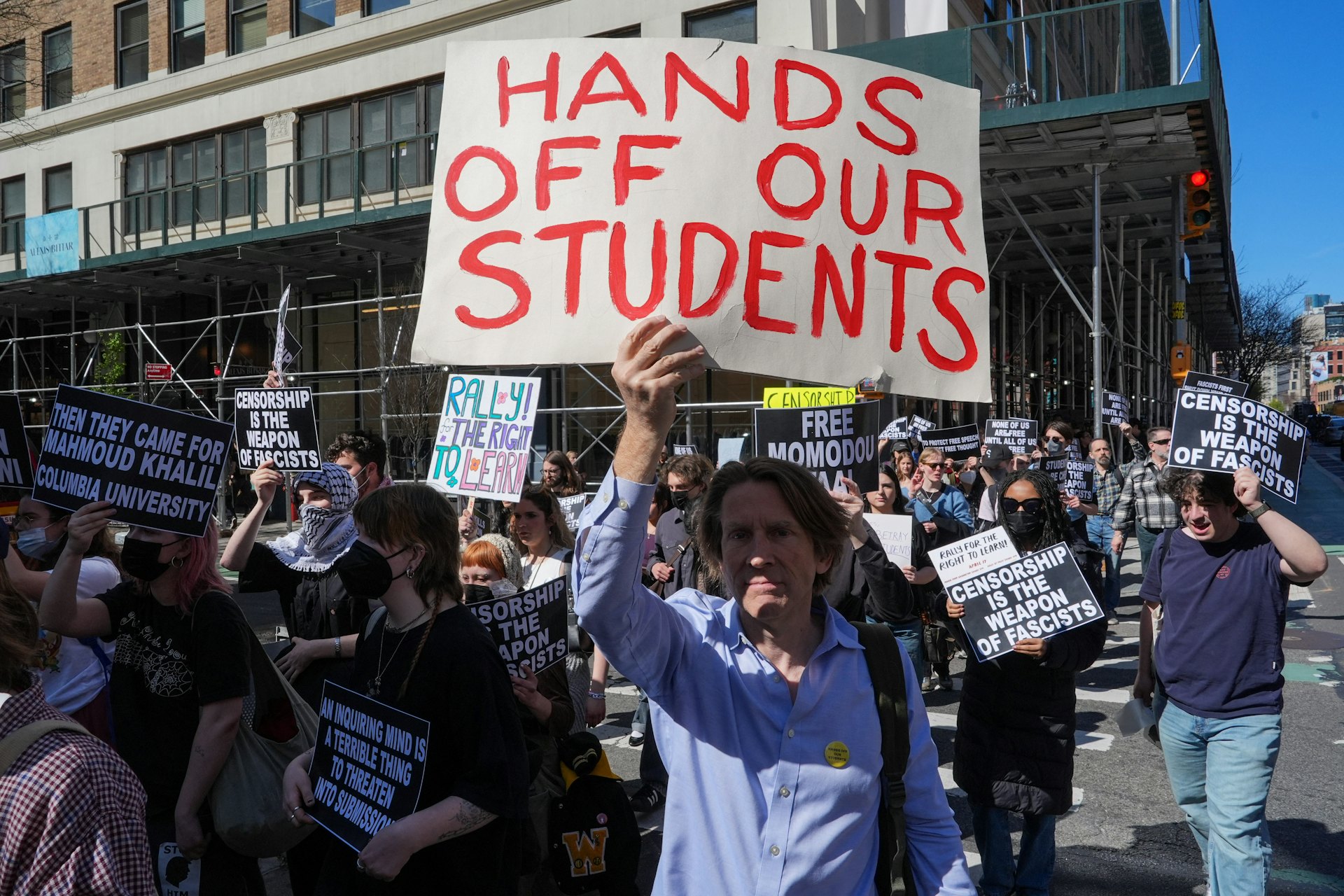 2025年4月17日，美國紐約市，哥倫比亞大學數學教授 Michael Thaddeus 在「爭取學習權利集會」遊行中舉着「別碰我們的學生」標語。（Reuters）