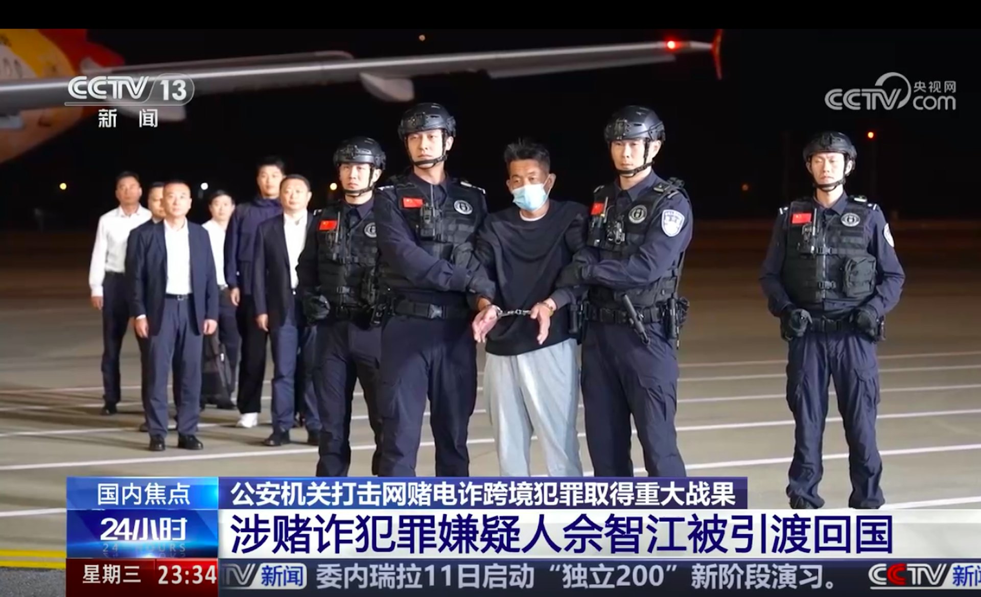 图为2025年11月12日，载著佘智江的客机昨晚降落南京禄口国际机场，他随即被警方锁上手扣，押解落机及离开。（央视截图）