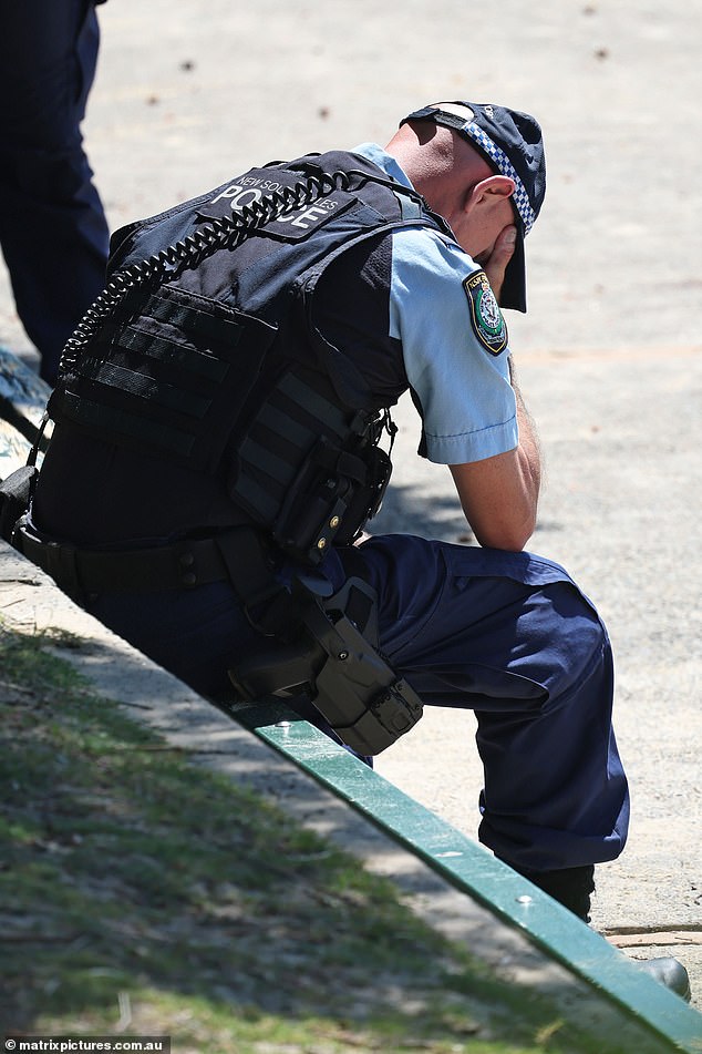 A distraught police officer sent to the scene of a fatal drowning has been pictured with his head in his hands amongst the chaos (pictured)