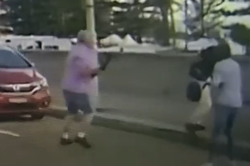 A man in a purple shirt briefly holds the firearm of the Bondi shooter.