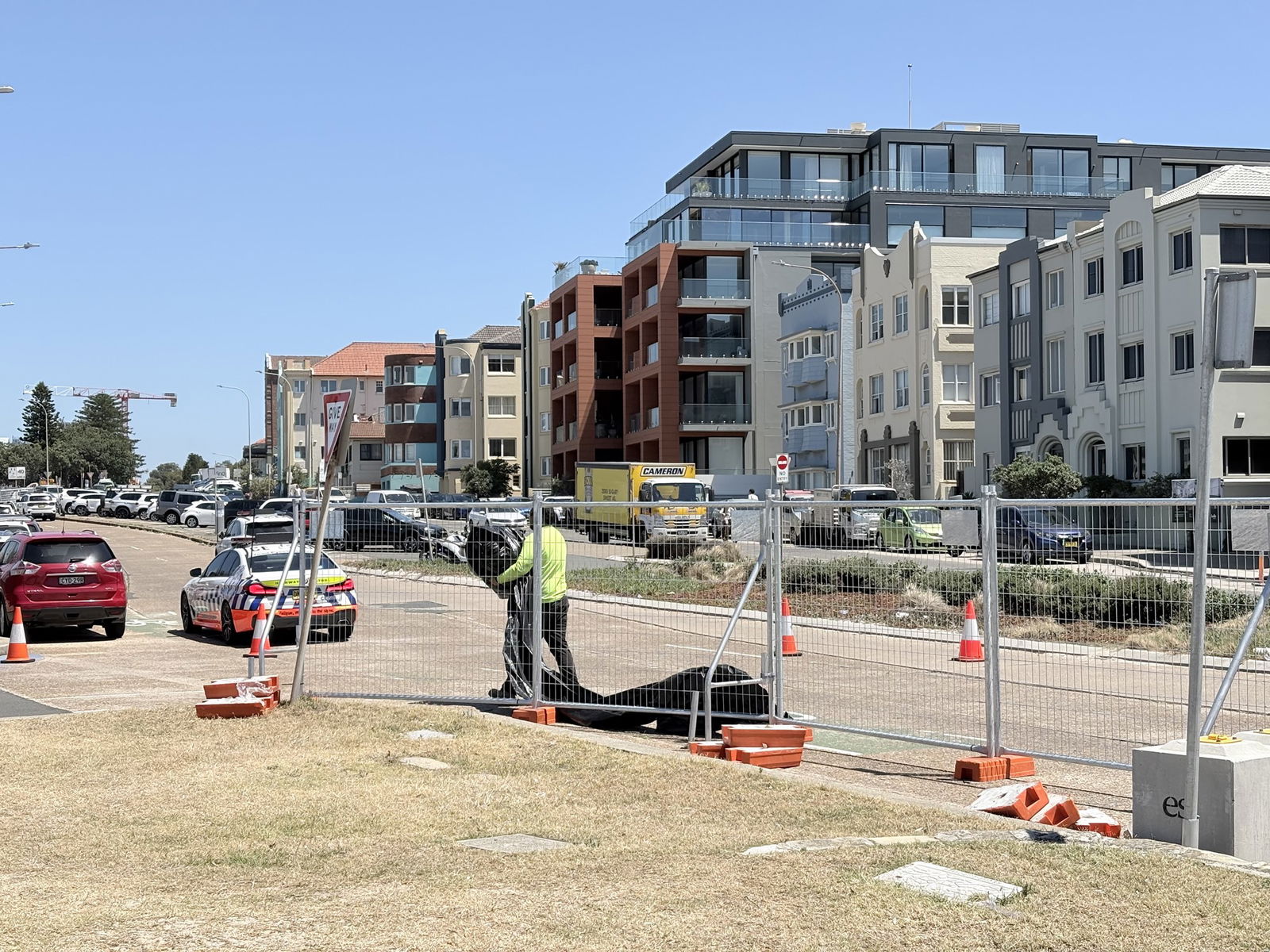 A man in a high vis shirt helps to remove tarps over fencing around the crime scene area.