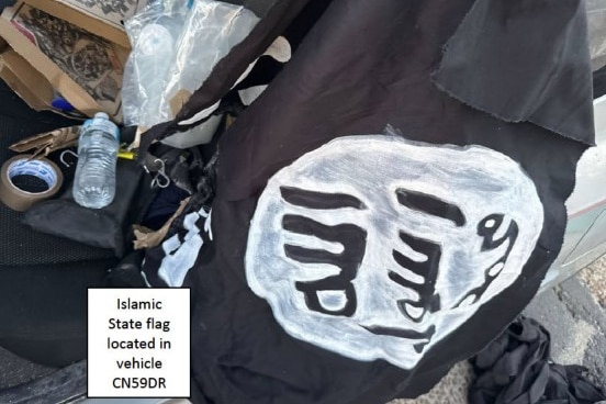 Homemade Islamic State flag in back of car driven by Bondi Beach gunmen, with pizza bpxed and water bottle also visible