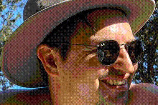 Close up of a man wearing a grey hat and dark sunglasses