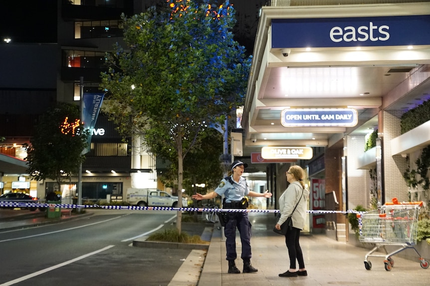 Police officer speaks to woman on empty street