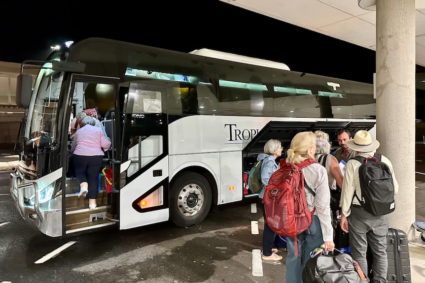People form a line outside a bus. 