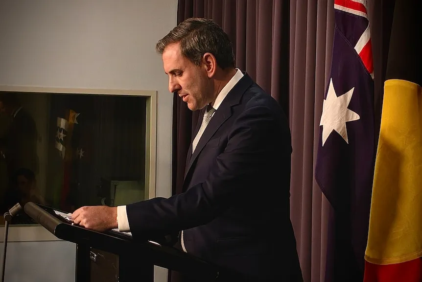 Jim Chalmers in a suit standing at a lectern