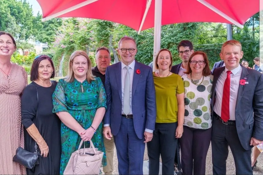 A group of men and women stand alongside the prime minister Anthony Albanese and NZ counterpart Chris Hipkins smiling