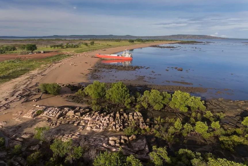 A wide shot of a beach with a barge parked