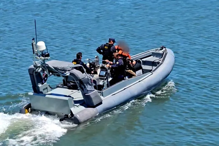 A rubber ducky style boat speeds off with men aboard.