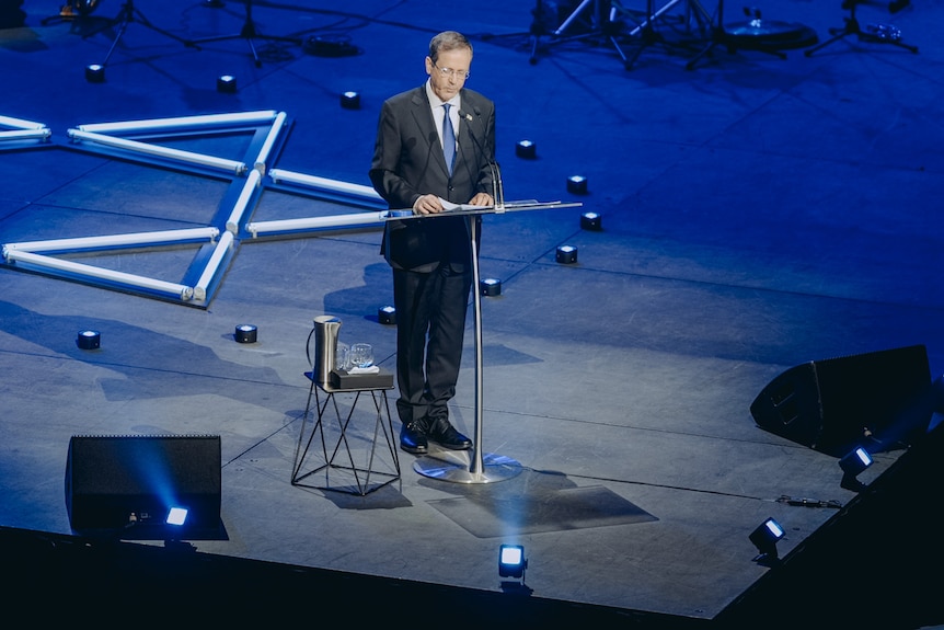 Isaac Herzog stood on stage wearing a suit and tie