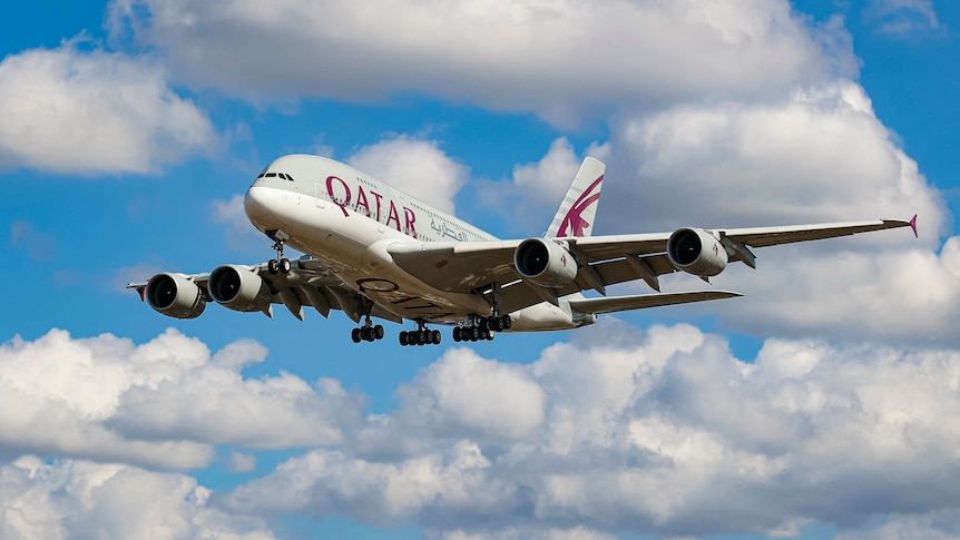 A Qatar Airways Airbus plane flying in a blue sky with white clouds.