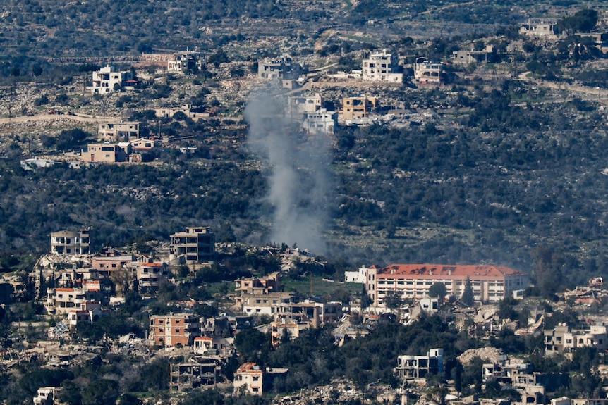 A wide shot of smoke rising in a mountainous village.