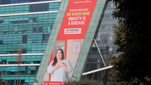 在印度古尔冈的一栋建筑上，一块广告看板上画着一位身穿束腰外衣、双手放在胸前的女性。广告词写道：“这不是我们的错。我们现在知道肥胖是一种疾病。”
