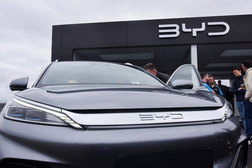 People looking inside the interior of a medium-sized vehicle at a car dealership.