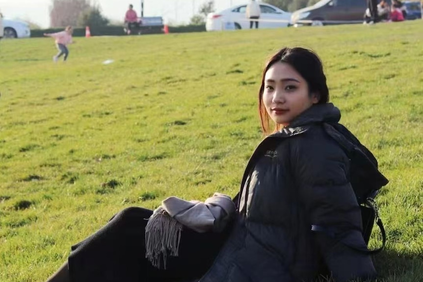 a young woman siting on grass outdoors